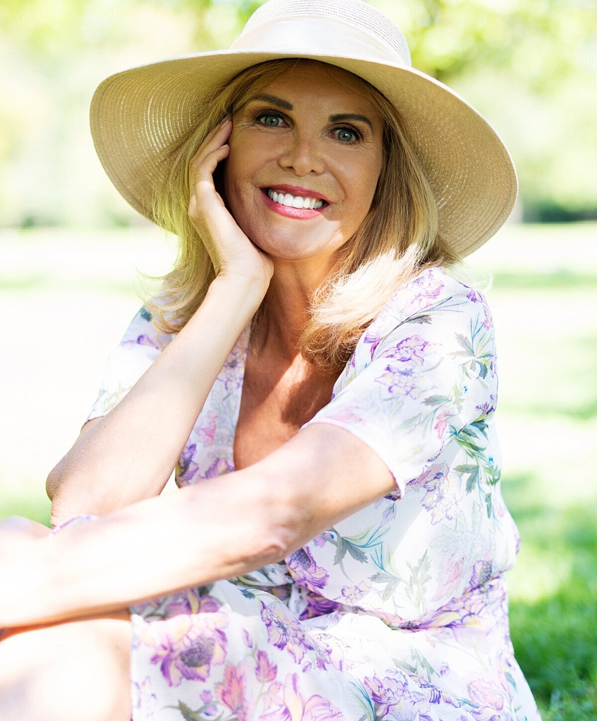 Smiling woman in a floral dress and hat.