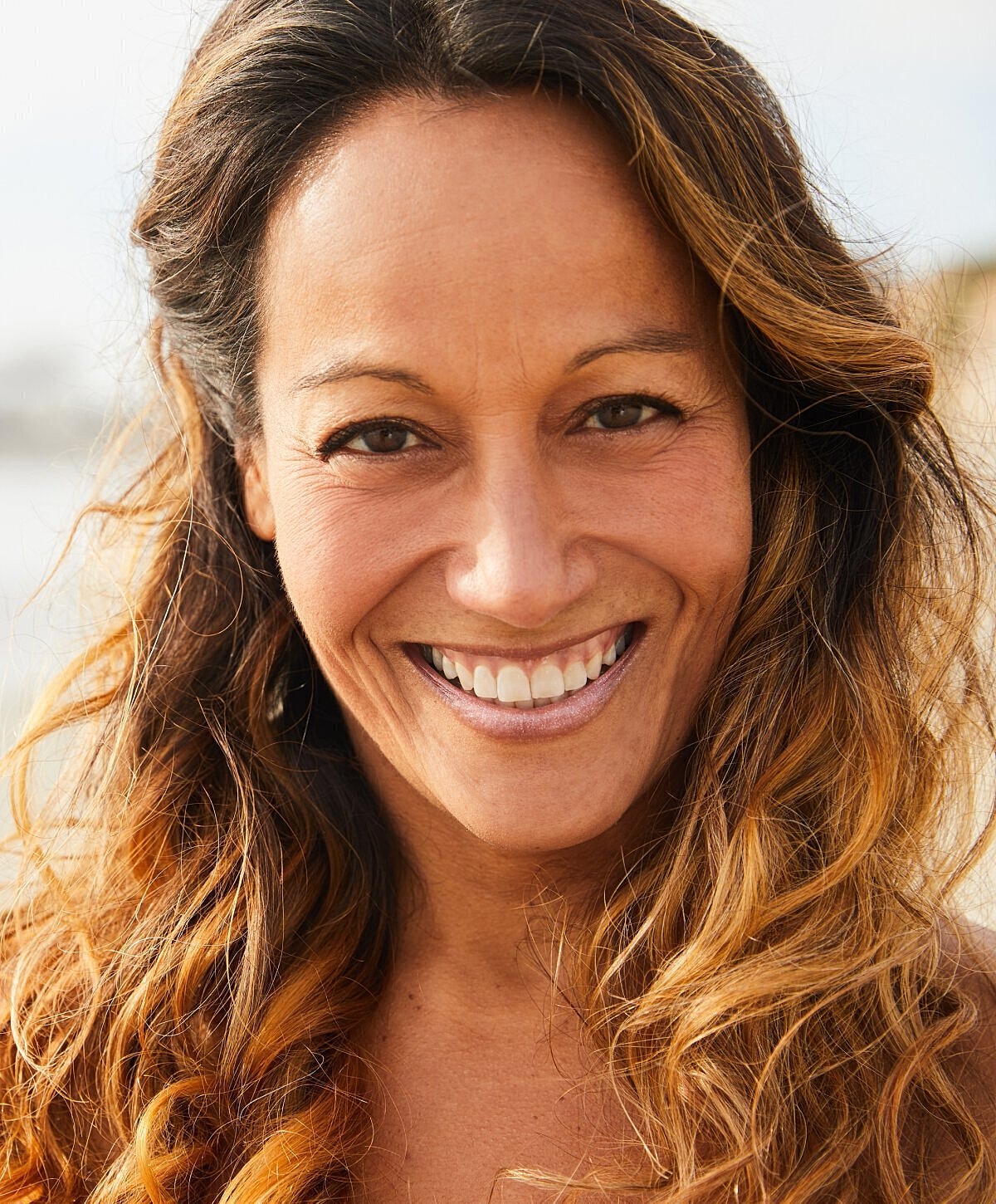 Smiling woman with wavy, long brown hair.