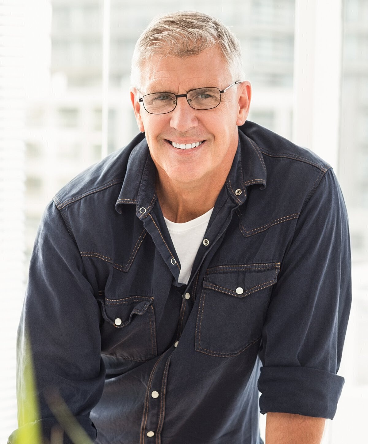 Smiling man in glasses, casual attire, indoors.