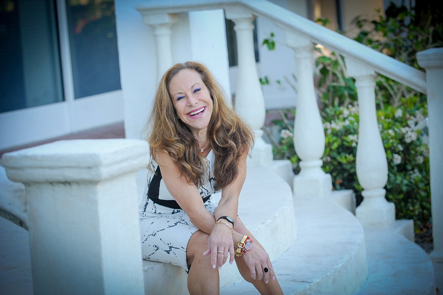 Woman smiling on stairs with decorative columns.