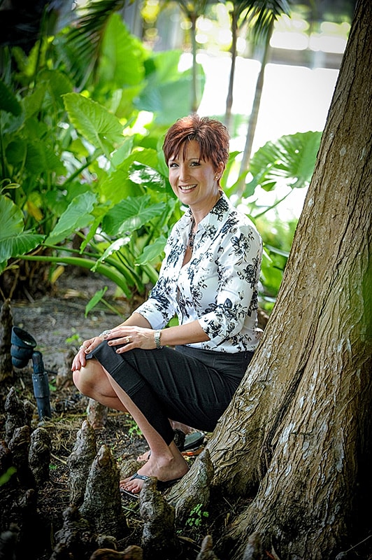 Woman sitting by tree in lush garden.