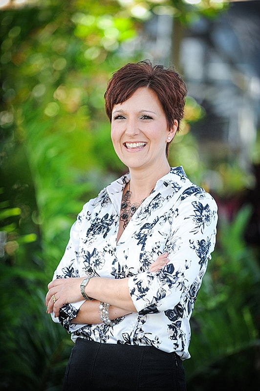 Smiling woman in stylish dress, arms crossed.