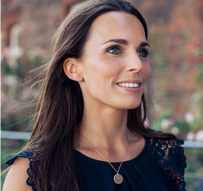 Smiling woman with long hair in outdoor setting.
