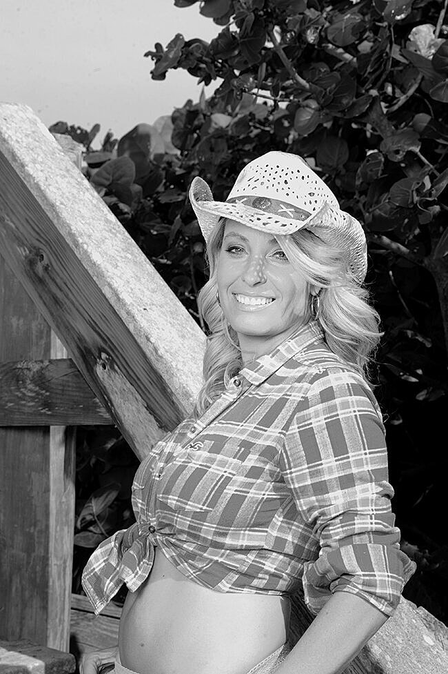 Woman in cowboy hat beside wooden structure.