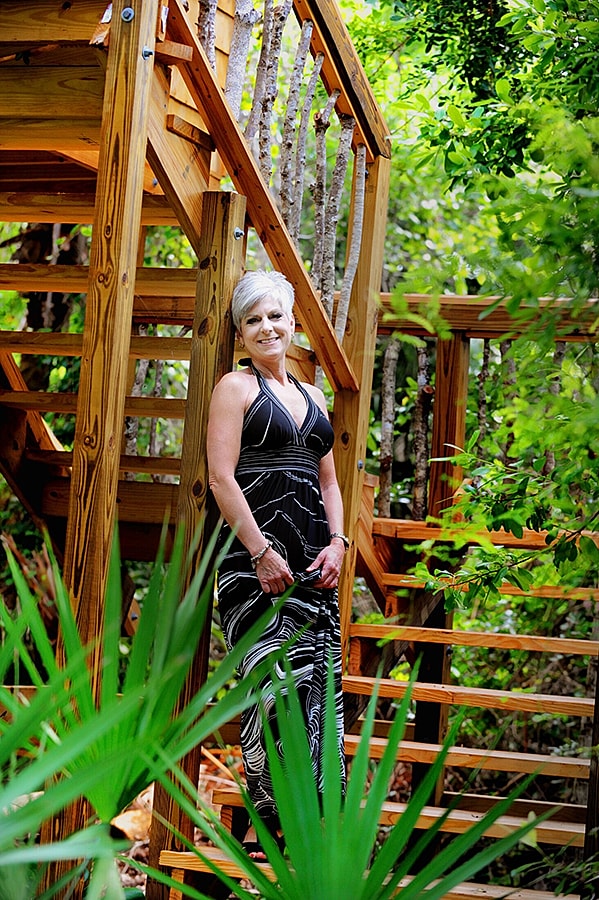 Woman in dress by wooden stairs in nature.