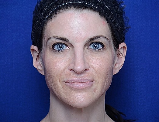 Woman with blue eyes against blue background.
