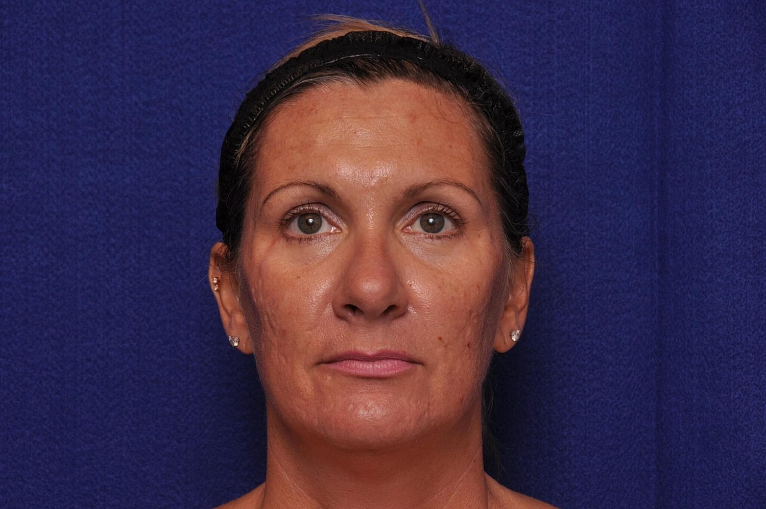 Elderly woman with curly hair against blue background.