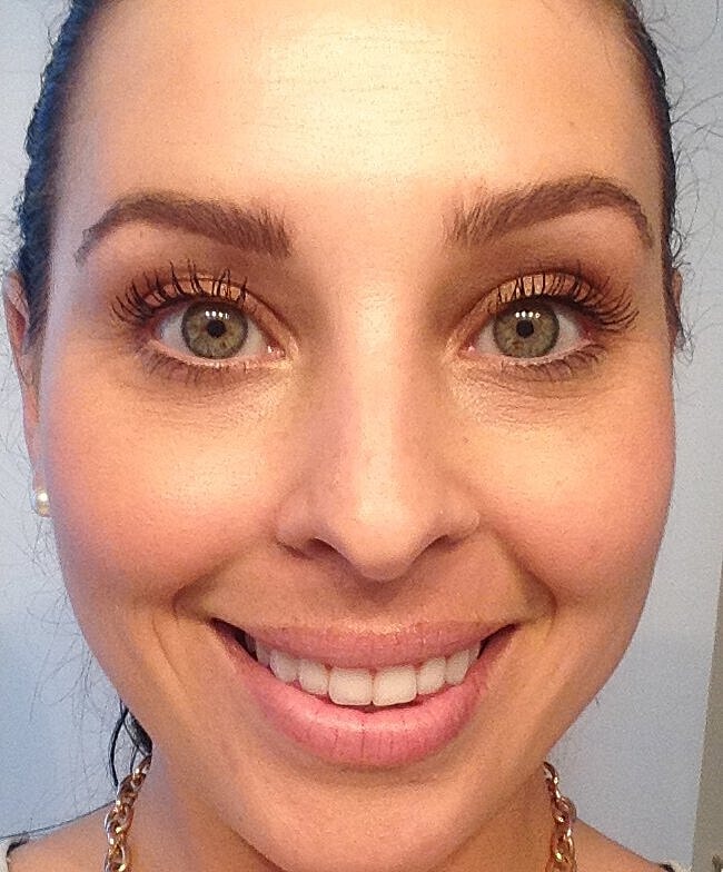 Smiling woman with green eyes and light makeup.