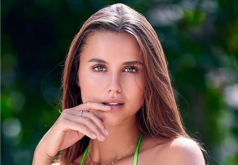 Woman with long hair posing thoughtfully outdoors.