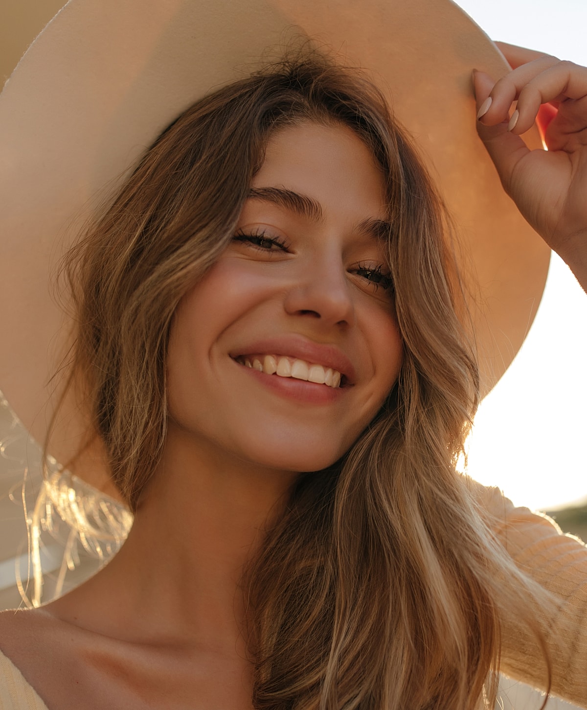 Smiling woman wearing a wide-brimmed hat.