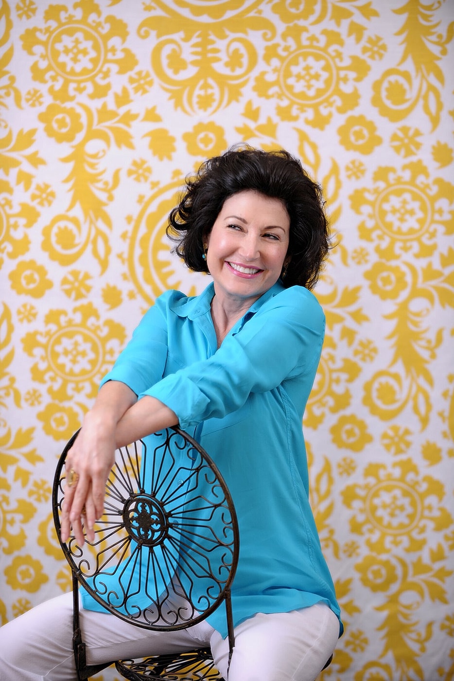 Smiling woman in stylish dress, arms crossed.