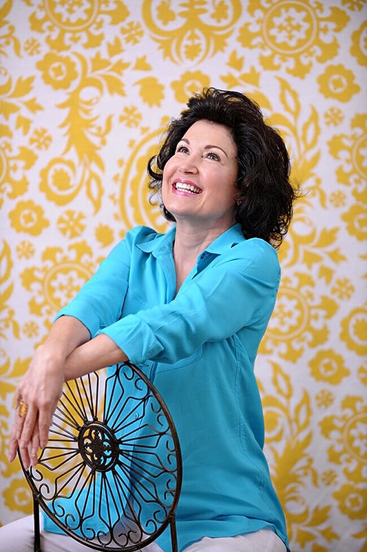 Woman smiling in front of yellow patterned background.
