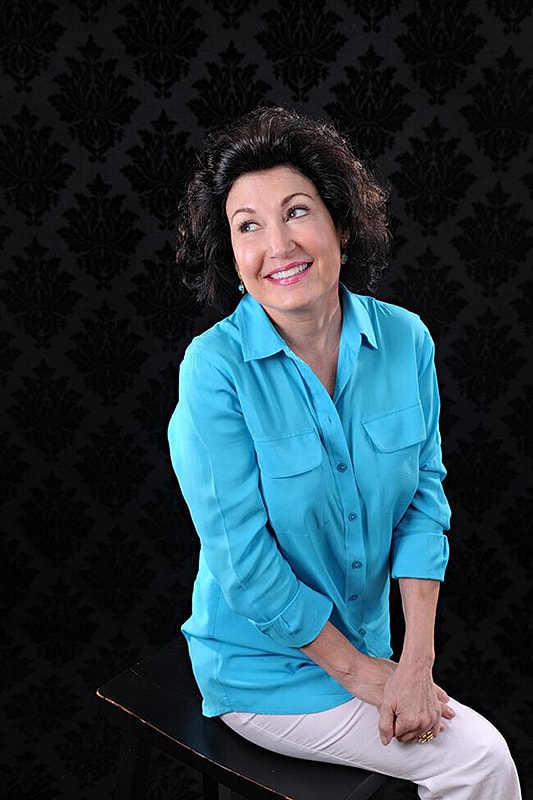 Smiling woman in blue shirt against dark background