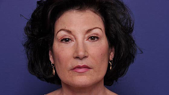 Woman with dark curly hair against purple background.