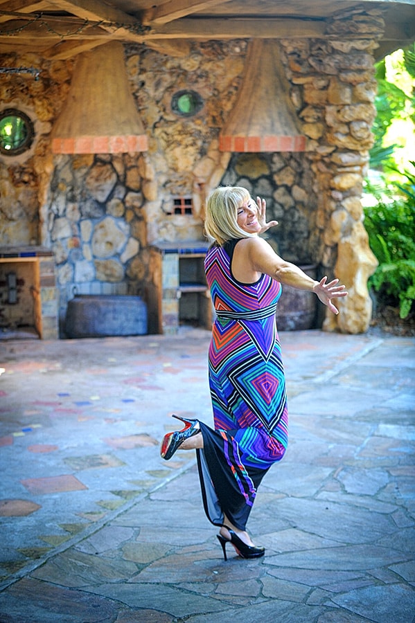 Woman in colorful dress striking a playful pose.