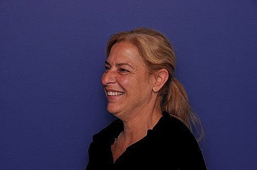 Smiling woman against a purple background.