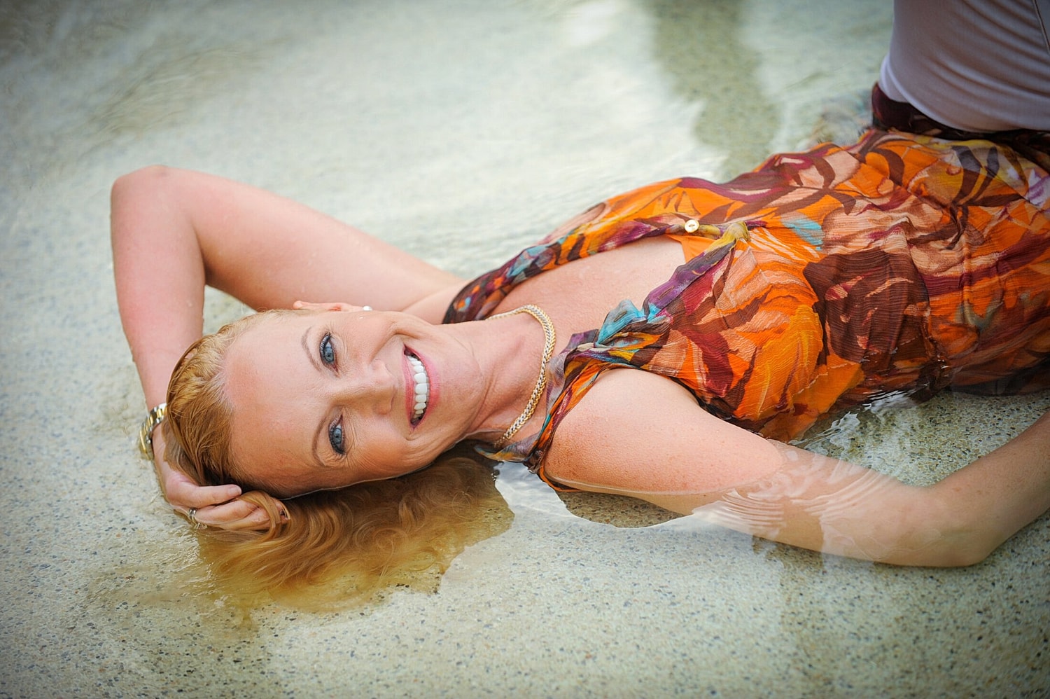 Woman smiling in water with floral dress.