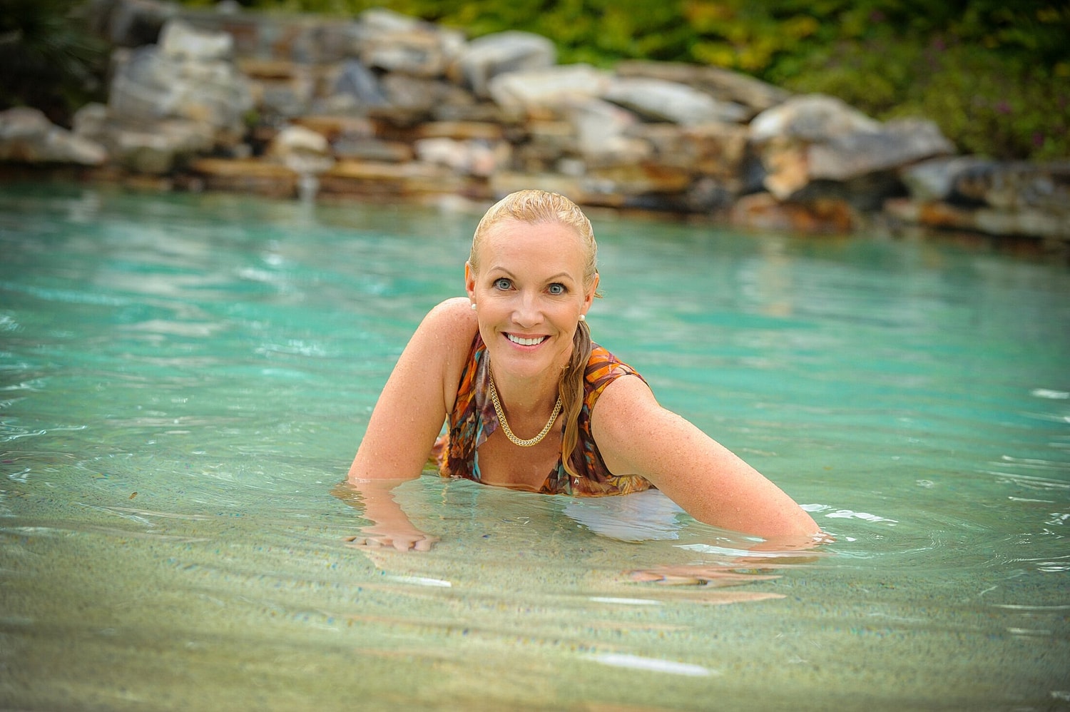 Smiling woman enjoying a tranquil pool setting.