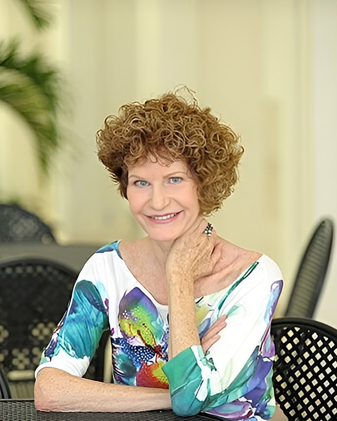 Smiling woman in stylish dress, arms crossed.