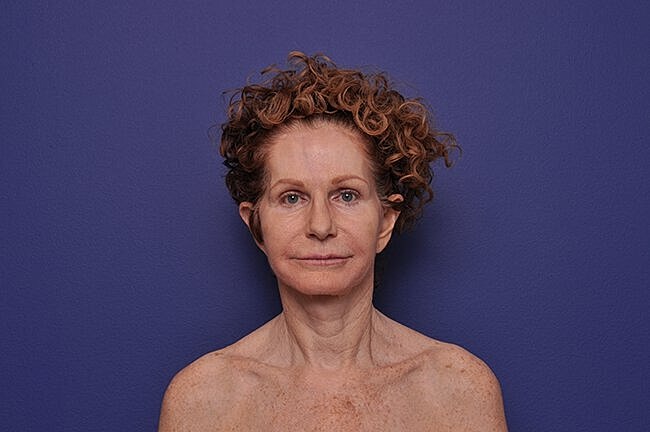 Woman with curly hair against purple background.