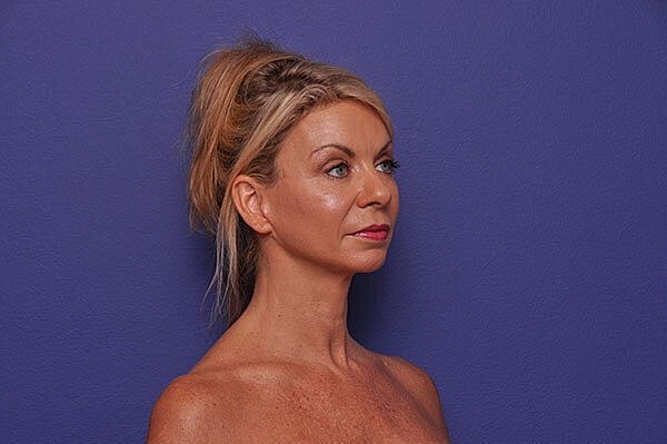 Woman with blonde hair against purple background.