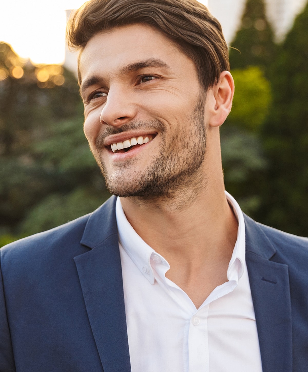 Smiling man in a suit outdoors during sunset.
