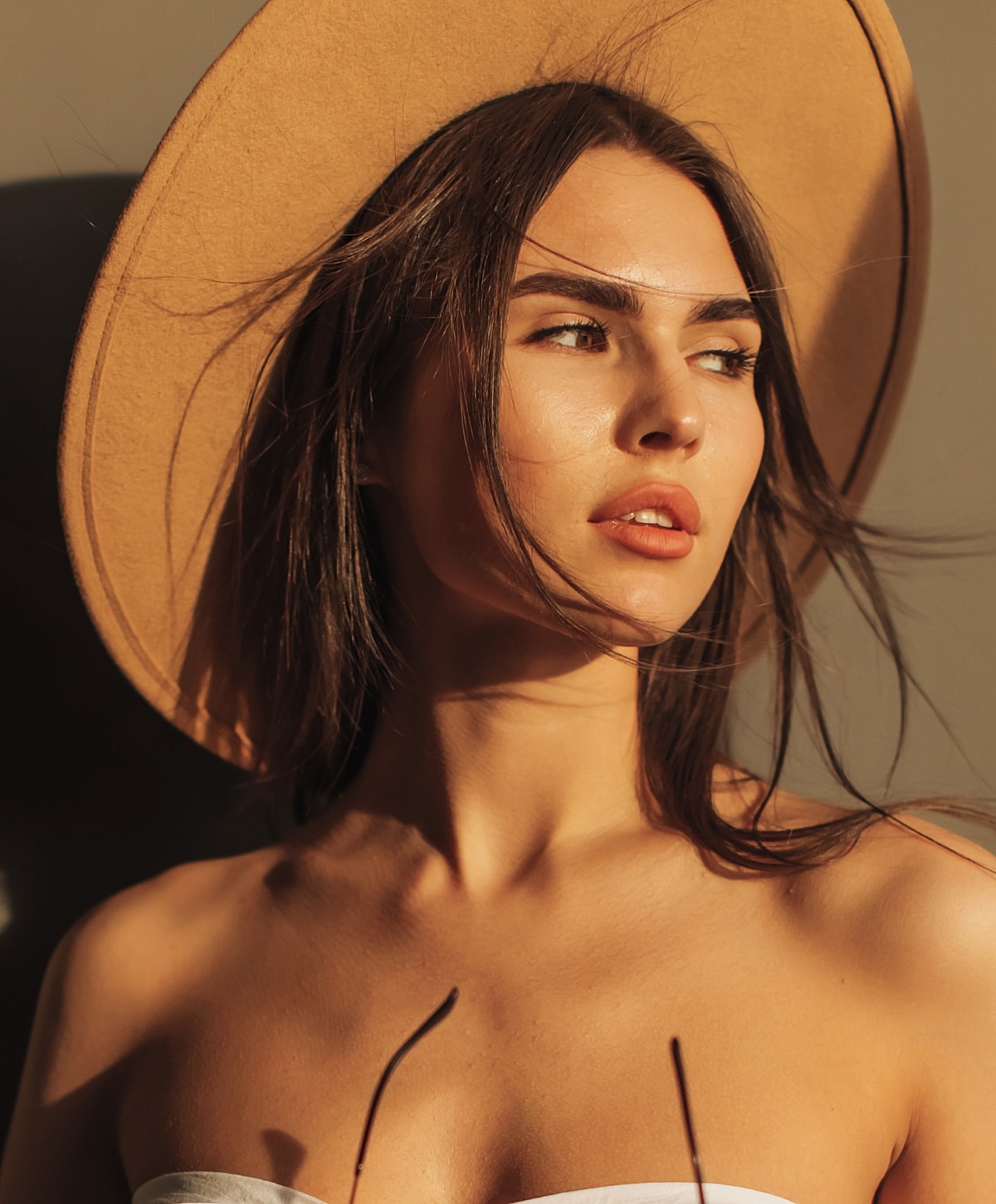 Woman in a sun hat, enjoying natural light.