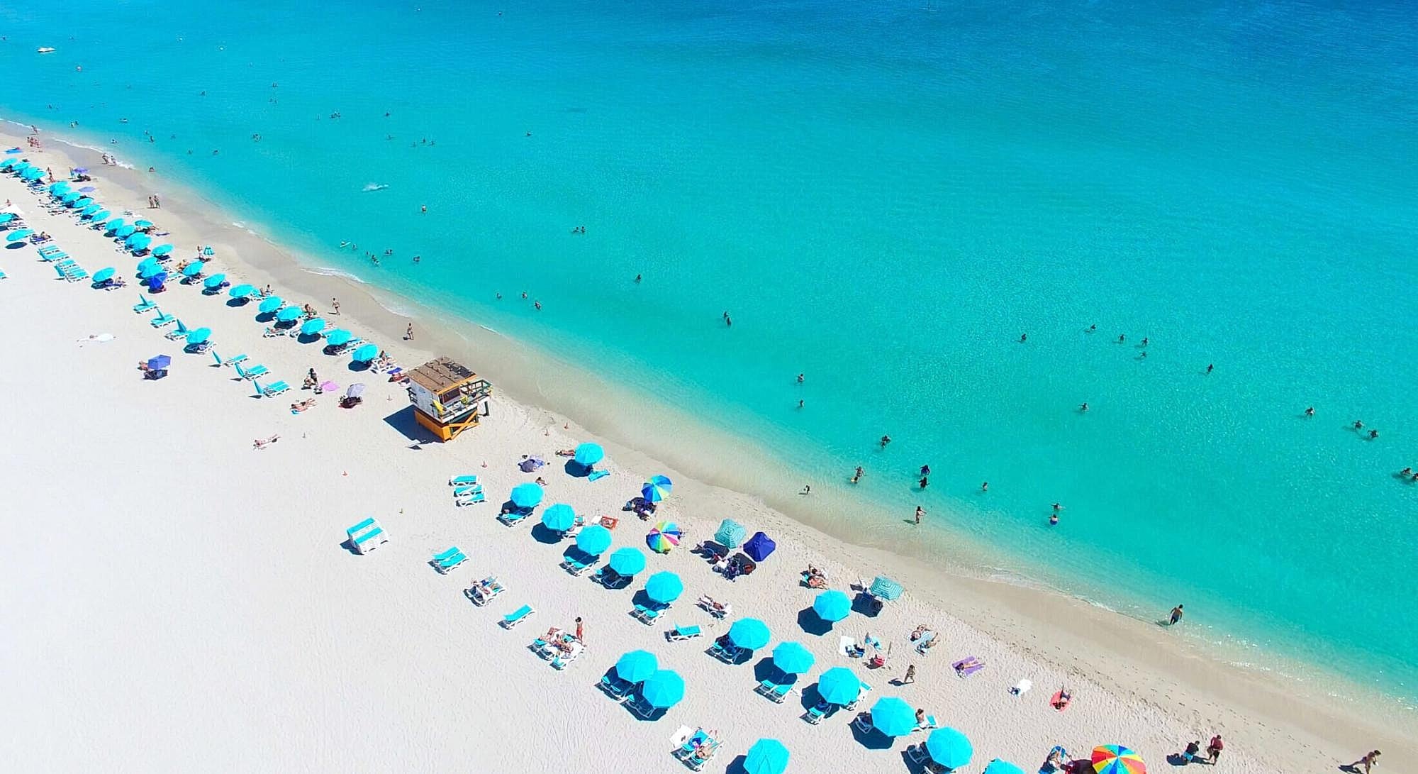 Tropical beach with umbrellas and clear turquoise water.