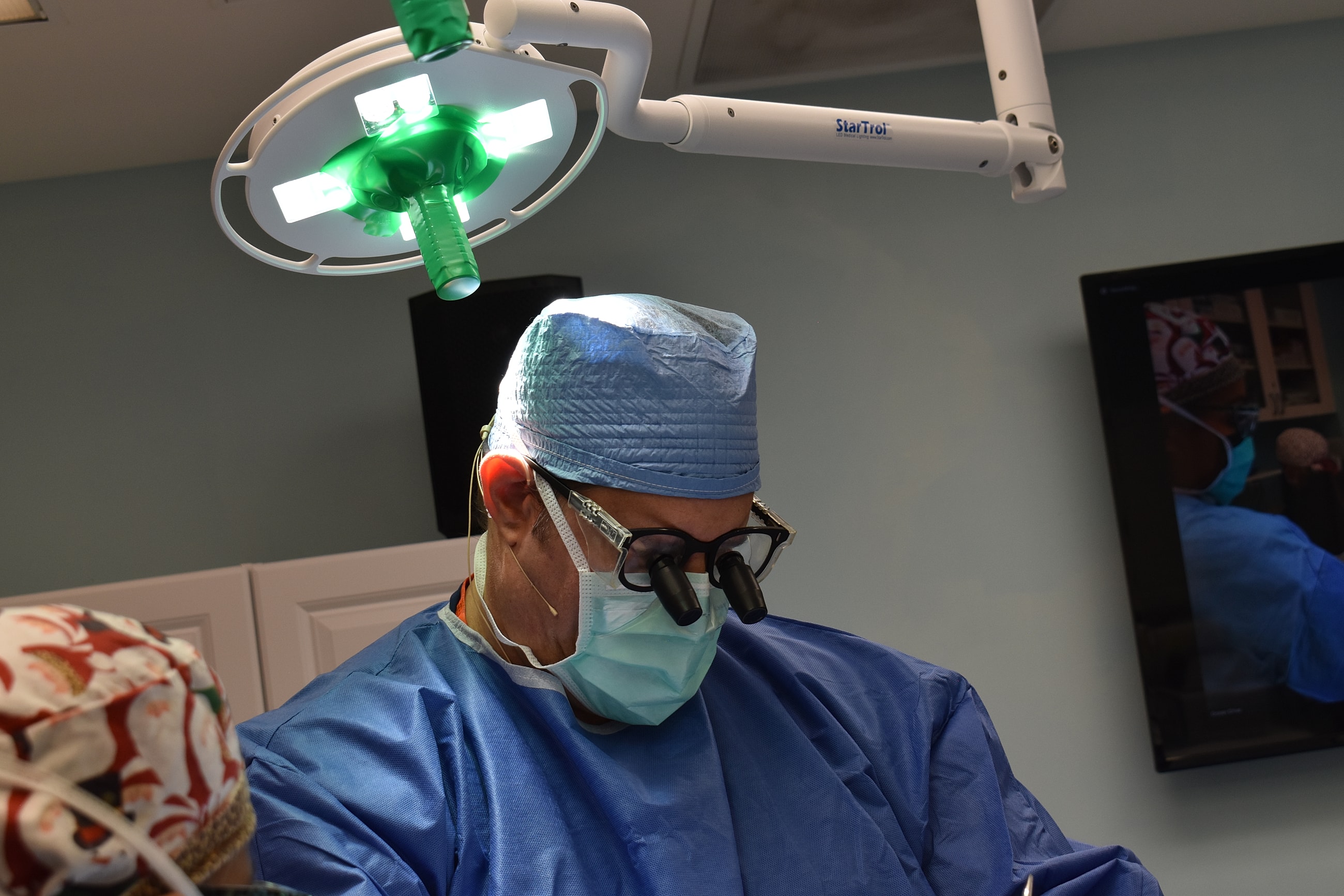 Surgeon wearing magnifying glasses in operating room.