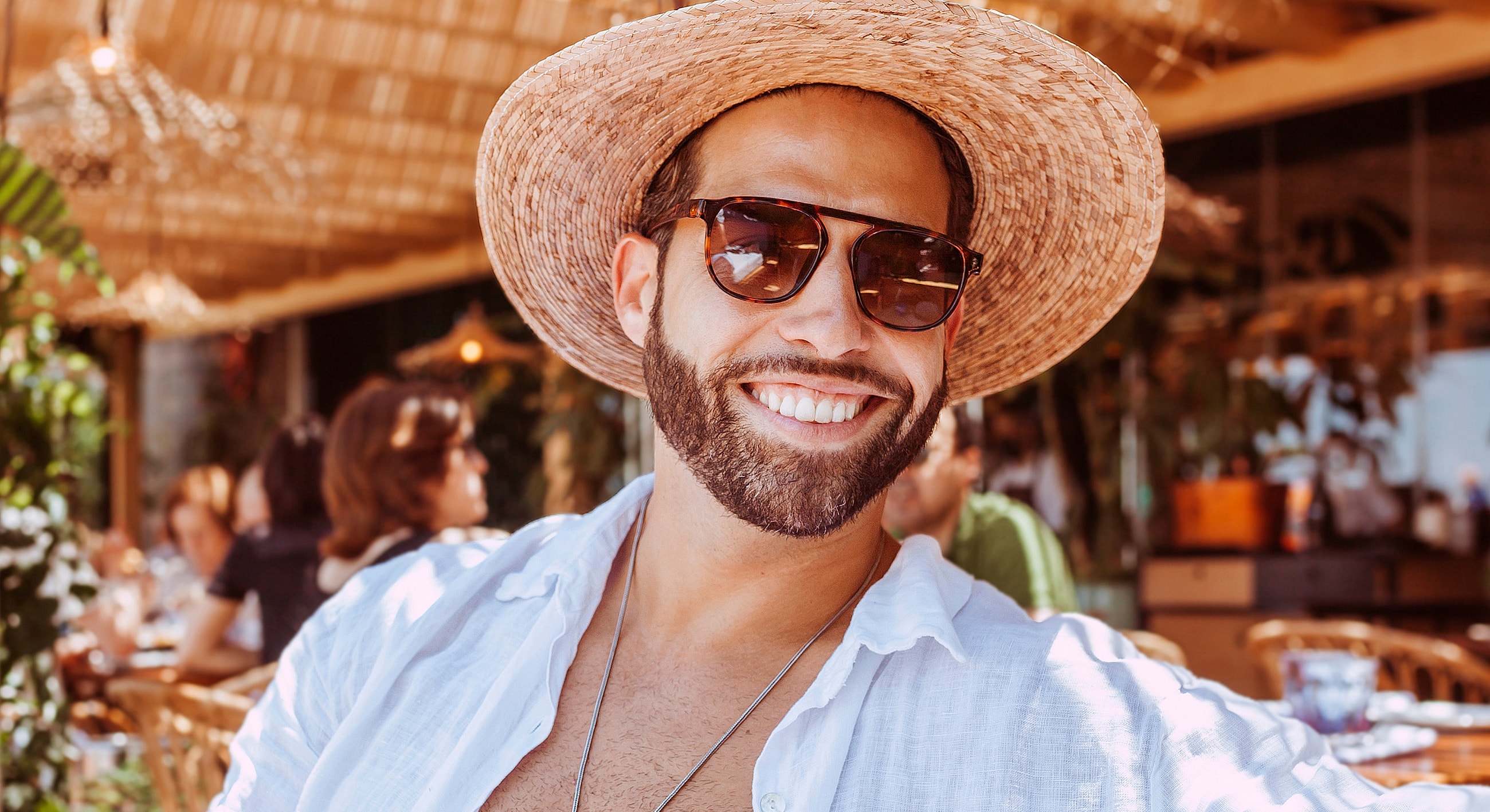 Smiling man wearing sunglasses and straw hat.