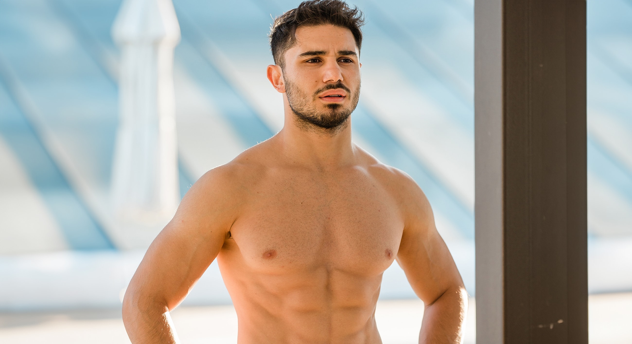 Shirtless man posing outdoors in natural light.