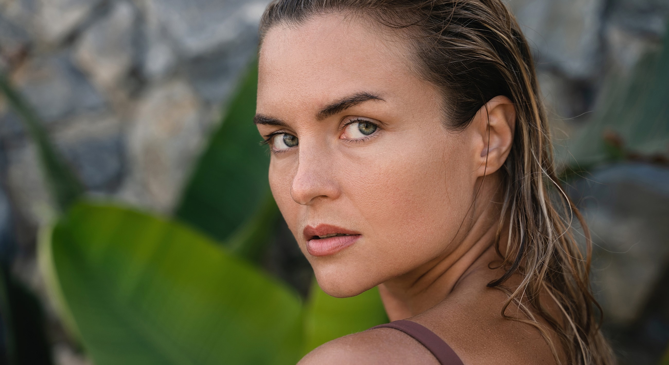 Woman with wet hair against tropical backdrop.